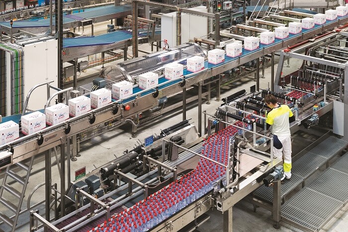 View of the Danone factory showing hundreds of bottles being processed and boxed