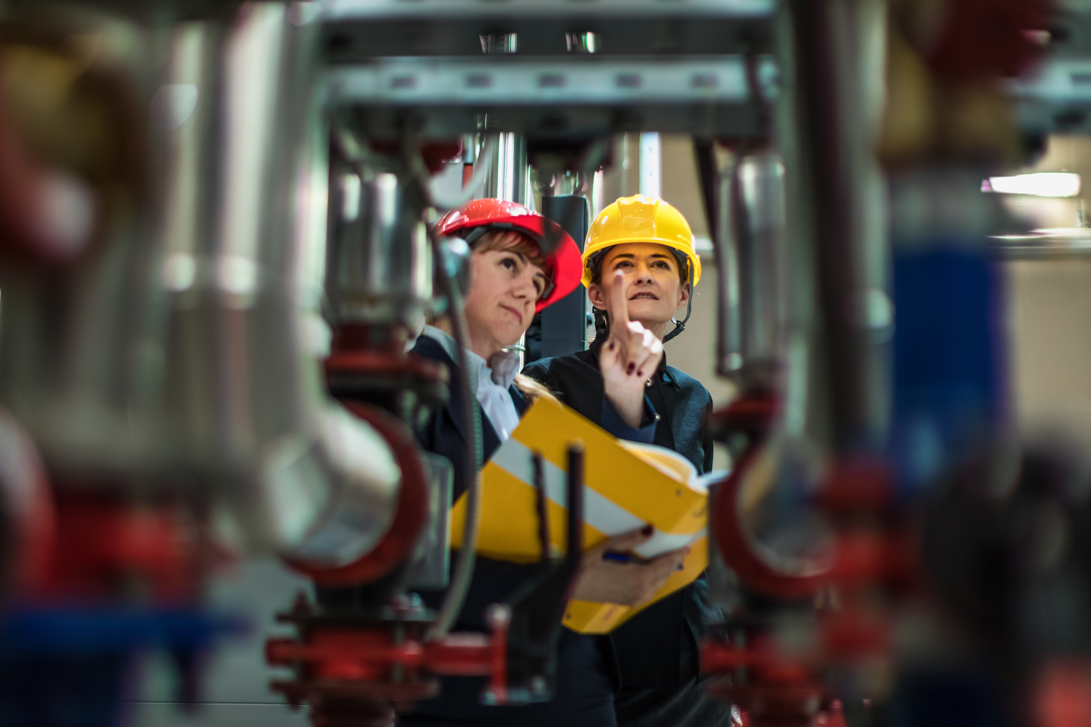 two people in hard hats looking up at equipment