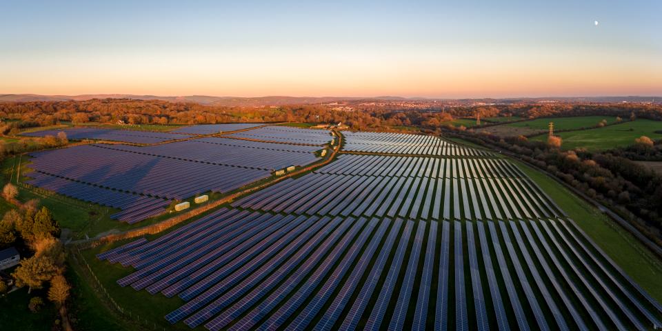 Aerial drone view of solar panels at a solar energy generation farm at Sunset in South Wales, UK