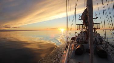 image of a ship sailing at sunset