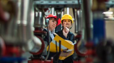two people in hard hats looking up at equipment