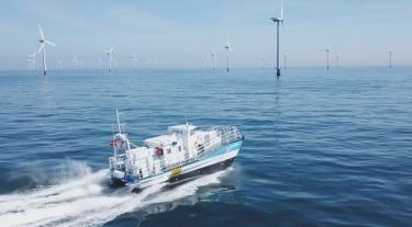 sea puffin vessel boat in the ocean heading towards offshore wind turbines
