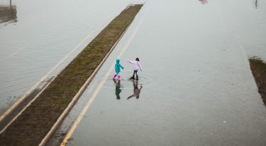 two children play in a flood on a road
